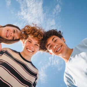 Low,Angle,View,Of,Funny,Smiling,Teenagers,Standing,And,Looking